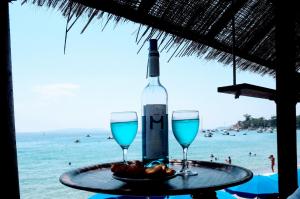 ル・ラヴァンドゥーにあるHôtelのビーチのテーブルに置かれたワイン1本とグラス2杯