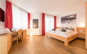 a bedroom with a large bed and red curtains at Avita - suites to relax in Ortisei