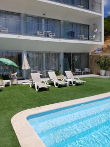 a swimming pool with lounge chairs and a building at Casa Praia Mar in Salema