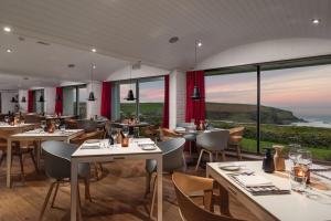 
a restaurant with tables and chairs and people eating at Bedruthan Hotel & Spa in Newquay
