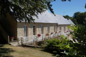 une ancienne maison en pierre avec une clôture blanche et des fleurs dans l'établissement Le Clos Saint Jean, à Sainte-Honorine-des-Pertes