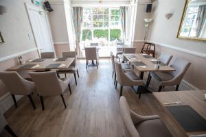 a restaurant with wooden tables and chairs and a window at The Corner House Hotel in Horley