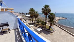 balcón con vistas a una playa con palmeras en Apartamentos La Perla Azul, en Málaga