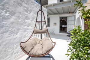 Plaka Suites في بلاكا ميلو: كرسي معلق مع الوسائد على الفناء