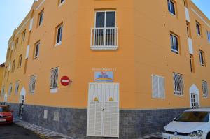 a orange building with a white door and a car parked in front at Armonía Beach 17 in Arinaga
