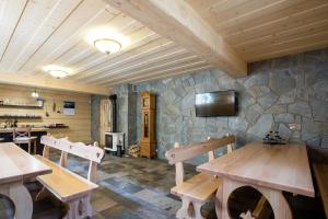 Cette chambre est dotée de tables en bois et d'un mur en pierre. dans l'établissement Domek za Strugiem - pokoje i apartamenty, à Zakopane