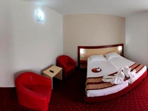 a hotel room with a bed and two red chairs at Hotel Solymar in Mangalia