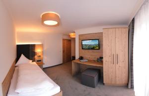 a room with a bed and a desk with a monitor at Hotel Birkenhof in Saalbach-Hinterglemm
