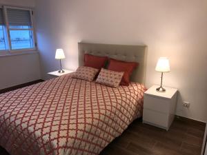 1 dormitorio con 1 cama con almohadas rojas y 2 lámparas en Rua Conselheiro Bivar, en Faro