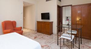 a bedroom with a bed and a tv and a chair at Apartamentos Vértice Bib Rambla in Seville