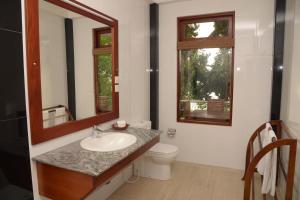 a bathroom with a sink and a toilet and a mirror at Riverside Inn Fuji in Bentota