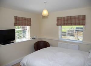 a bedroom with a white bed and two windows at The Mulberry Inn in Llansantffraid Glyn Ceiriog