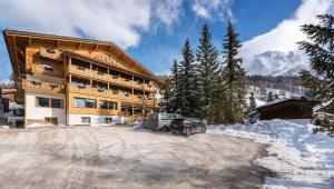 a large building with a car parked in the snow at La Stua in San Cassiano
