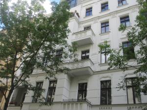 - un bâtiment blanc avec des fenêtres et des arbres dans l'établissement Berlin Prenzlauer Berg, à Berlin