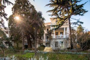 een groot wit huis met bomen ervoor bij Ligo Morskaya in Simeiz