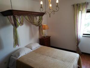 a bedroom with a bed with a chandelier and a window at Sintra/Colares Beach House with Mountain View in Sintra