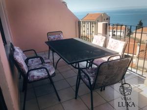 a table and chairs on a balcony with the ocean at Apartments Villa Luka in Sveti Stefan