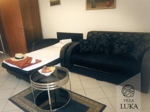 a living room with a black couch and a table at Apartments Villa Luka in Sveti Stefan