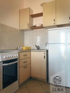a kitchen with a white refrigerator and a sink at Apartments Villa Luka in Sveti Stefan