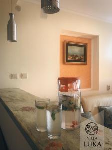 a table with three glasses and a vase on it at Apartments Villa Luka in Sveti Stefan