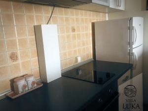 a kitchen with a black counter top and a refrigerator at Apartments Villa Luka in Sveti Stefan