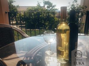 a glass table with a bottle of wine and a wine glass at Apartments Villa Luka in Sveti Stefan