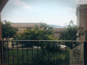 a fence in front of a building with trees at Apartments Villa Luka in Sveti Stefan