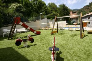 un patio con parque infantil con tobogán y columpios en Hotel Sant Antoni en Ribes de Freser