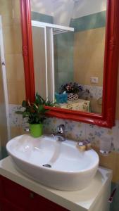 スペッキアにあるCasa vacanze Elisirのバスルーム(赤い鏡と植物付きの洗面台付)