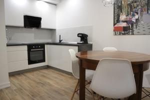 cocina con mesa de madera y sillas blancas en Apartamenty Tychy Slaskie Ogrody, en Tychy