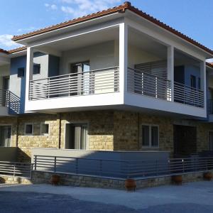 a house with a large balcony on the side of it at Nissos Rooms Ammouliani in Ammouliani