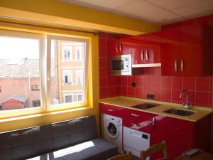 a kitchen with red cabinets and a sink and a window at Jimena in Burgos