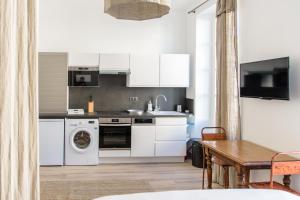 a kitchen with white cabinets and a washer and dryer at les appartements du 10 in Rochefort