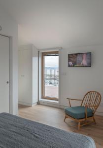 Un dormitorio con una cama y una silla y una ventana. en Hotel SempreFisterra, en Finisterre