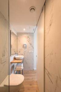 uma casa de banho com um WC branco e um lavatório. em Hotel SempreFisterra em Finisterre