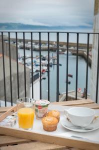 bandeja con un desayuno de zumo de naranja y magdalenas en el balcón en Hotel SempreFisterra, en Finisterre