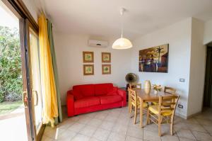 sala de estar con sofá rojo y mesa en A.I.R. Castelsardo Borgo di Mare, en Castelsardo