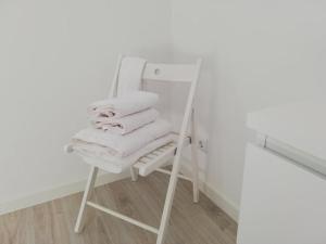 a stack of towels sitting on a chair next to a mirror at Azores Calheta Inn Apartment T3 in Ponta Delgada