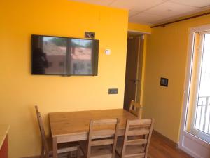 a dining room table with a television on a yellow wall at Jimena in Burgos