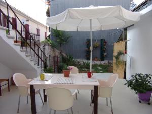 a white table with chairs and an umbrella on a patio at Finestra Rossa old town vintage house in Lefkada Town