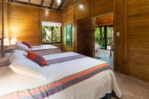a bedroom with two beds in a room with wooden walls at Villas El Encanto Cozumel in Cozumel