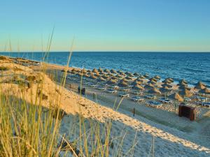 a beach with a bunch of umbrellas and the ocean at Hotel Quinta do Lago in Quinta do Lago