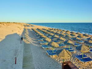 a row of beach chairs and umbrellas on a beach at Hotel Quinta do Lago in Quinta do Lago