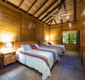 two beds in a room with wooden walls at Hotel Villas El Encanto Cozumel in Cozumel