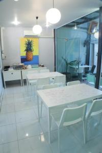 a dining room with white tables and white chairs at S'Prima Hostel in Phitsanulok
