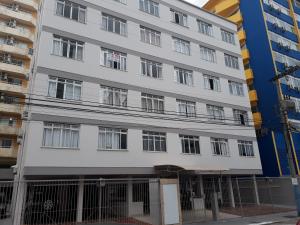 a white building with windows on a street at Ótimo Apto. 180 metros da Praia in Balneário Camboriú