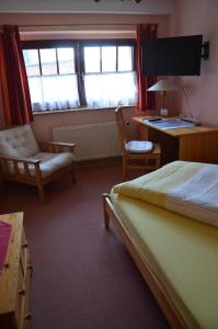 a bedroom with a bed and a desk and a chair at Hotel garni & Oma's Heuhotel 'Pension zur Galerie' in Barby