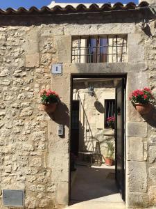 - un bâtiment en pierre avec une porte et des pots de fleurs dans l'établissement Le Case Dello Zodiaco albergo diffuso, à Modica