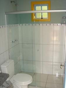 a white bathroom with a toilet and a shower at Pousada Vila Cocais in Cocais