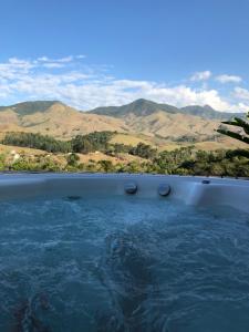 a large body of water with mountains in the background at Linda casa de frente para a Bocaina in São José do Barreiro